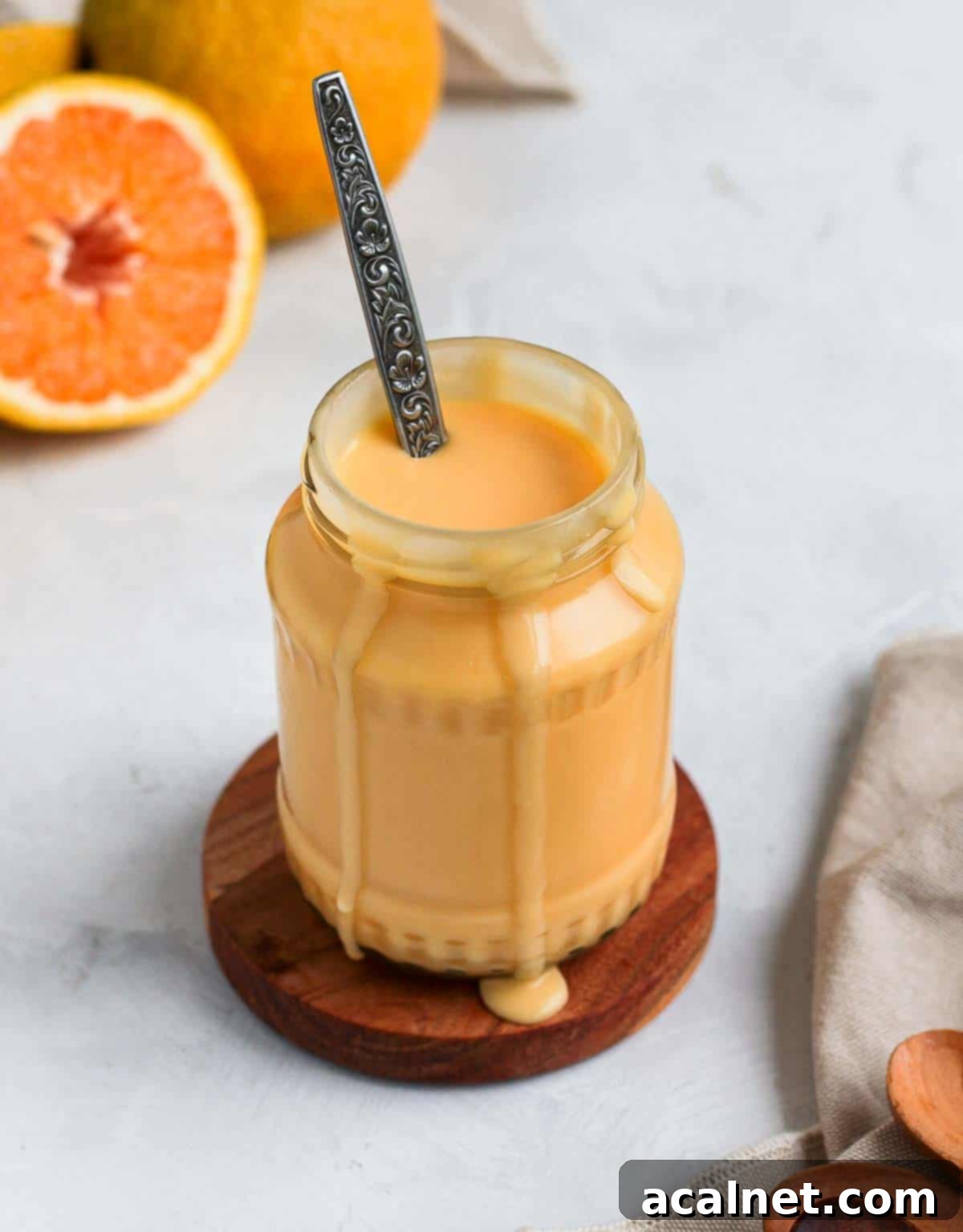 A vibrant bowl of orange curd viewed from above, elegantly surrounded by fresh, halved oranges, emphasizing its natural, fruity origin.