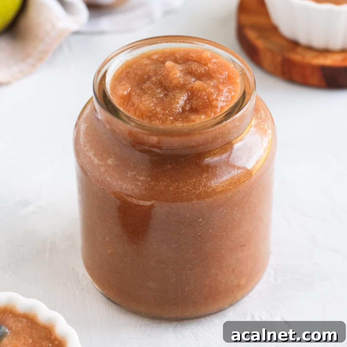 Close up on a glass jar filled with smooth, golden spiced pear compote, garnished with a fresh star anise, ready to be enjoyed.