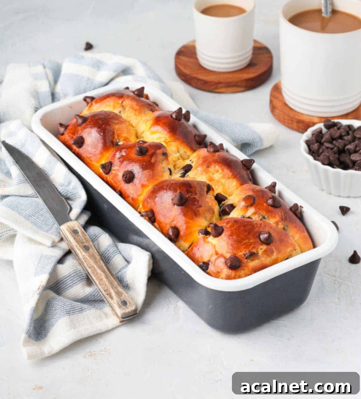 Baked Chocolate Chip Brioche Loaf in its baking pan, resting on a white and blue patterned napkin.