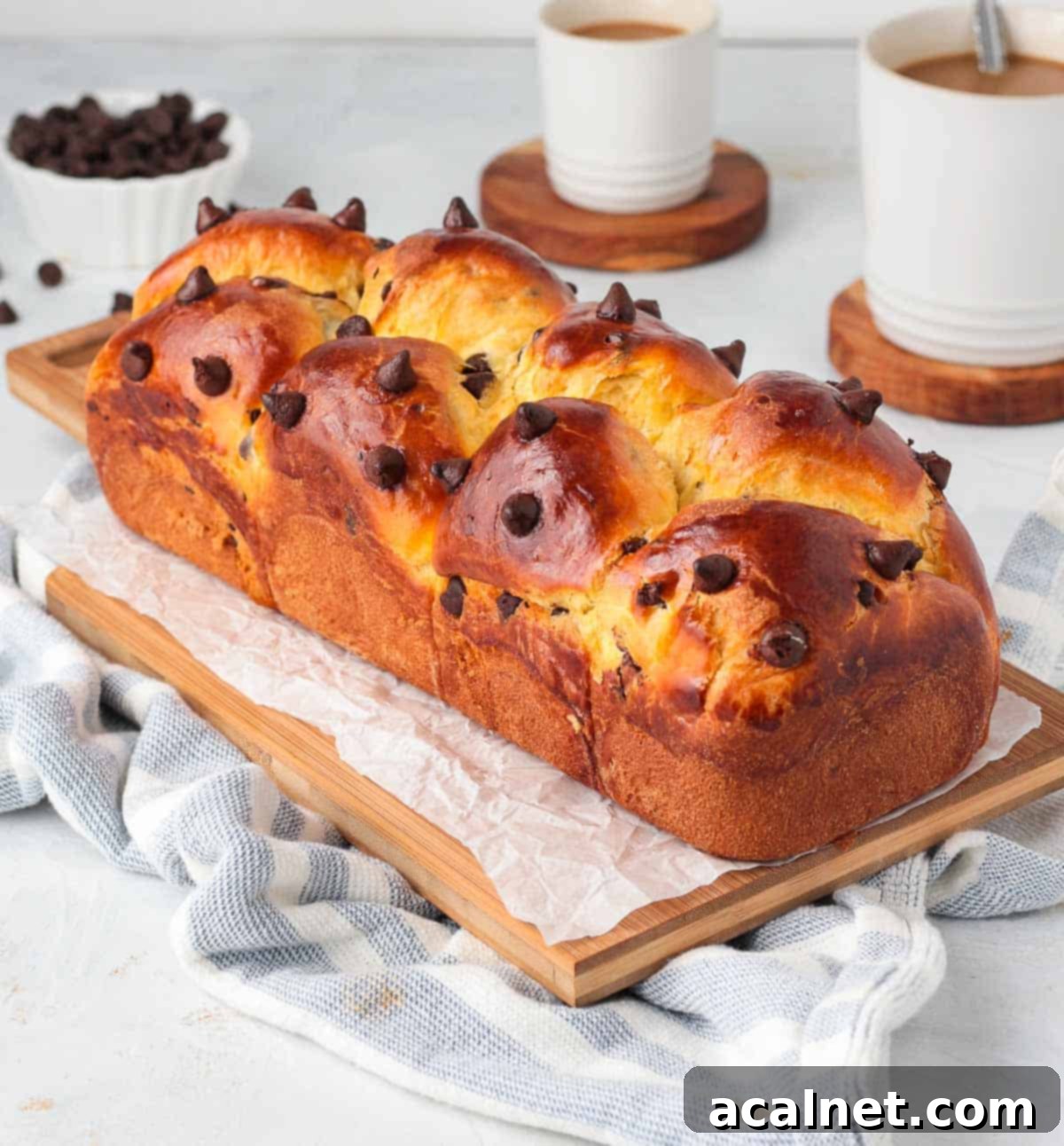 A full chocolate chip brioche loaf on a rustic wooden cutting board, ready to be sliced.