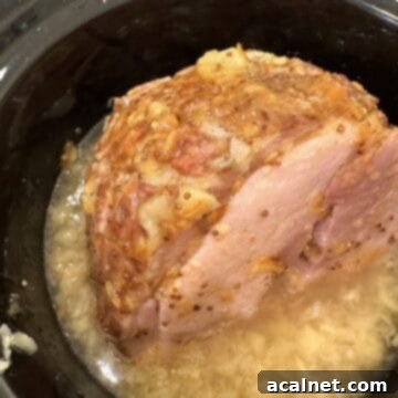 A cooked ham with marmalade glaze on top and crushed pineapple.