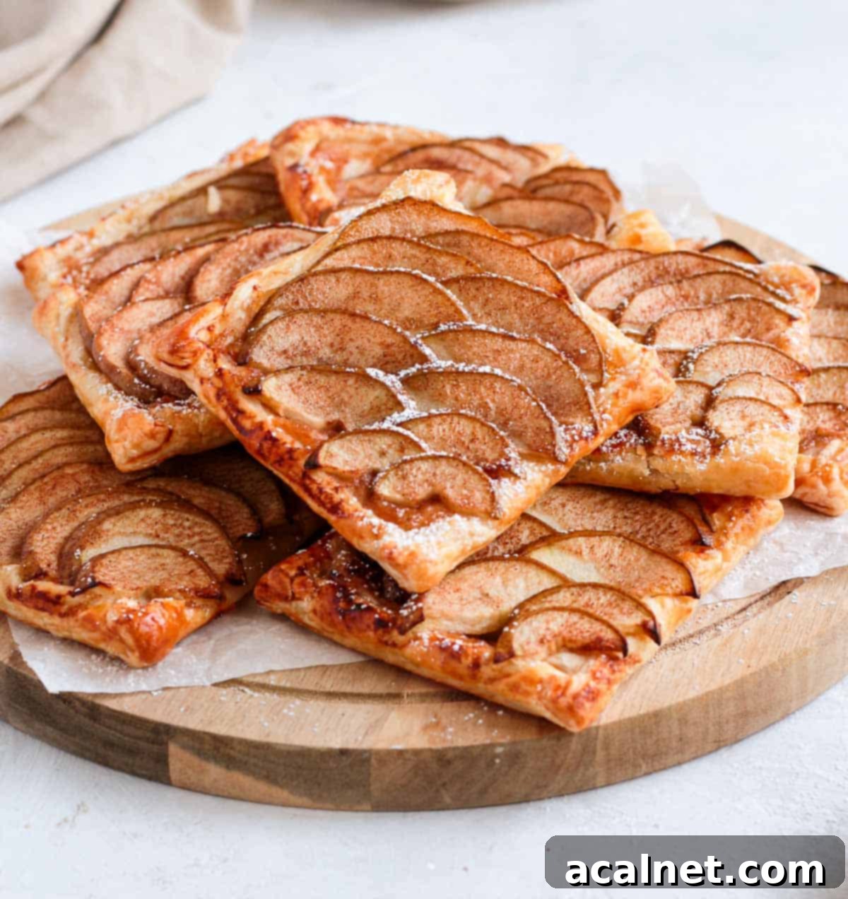 Stack of tarts on a round wooden board.