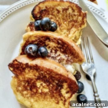 Three slices of buttermilk french toast on a plate with berries on top.