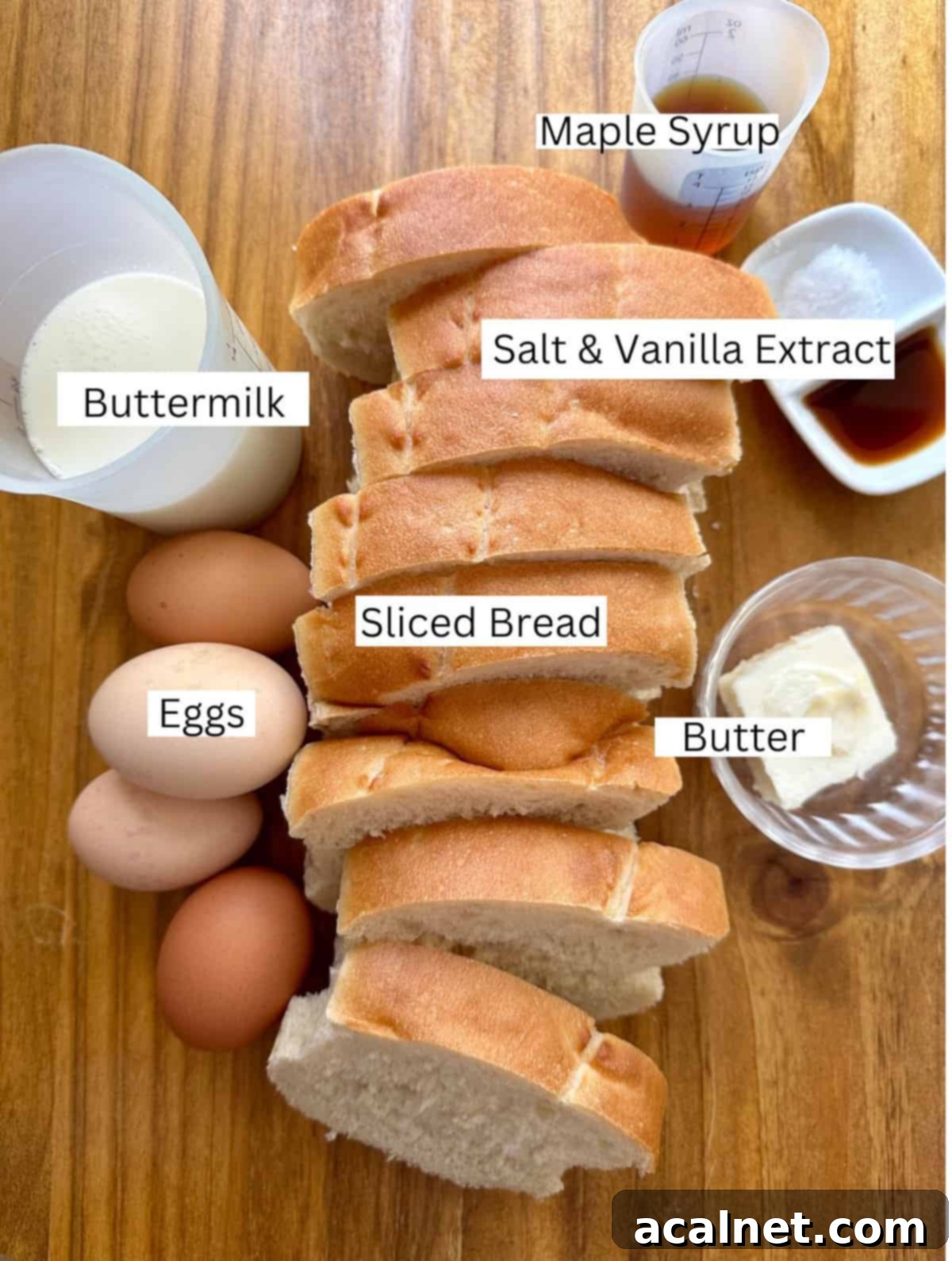 Ingredients for buttermilk french toast on a cutting board including bread slices, eggs, a jug of buttermilk, and a bottle of maple syrup.