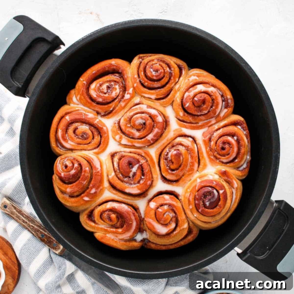 Cinnamon rolls inside the remoska bowl from above, glazed with icing.