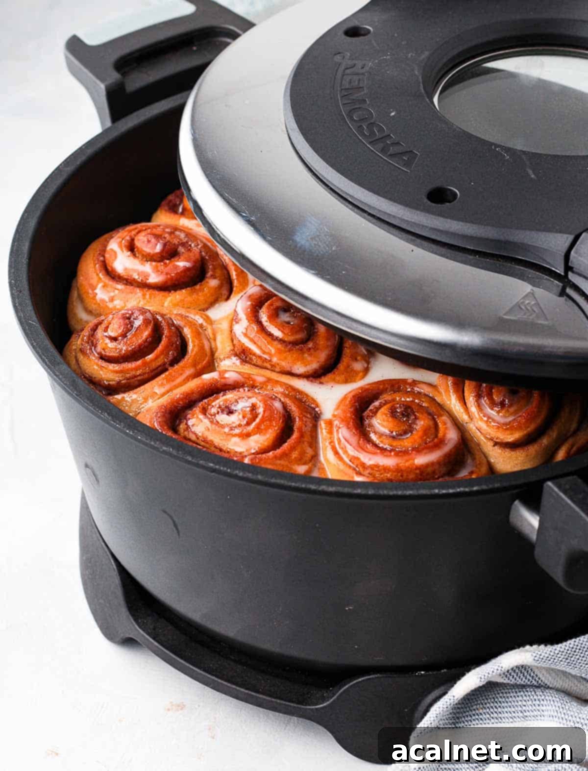 Lifting the remoska lid off the pot with the baked scrolls.
