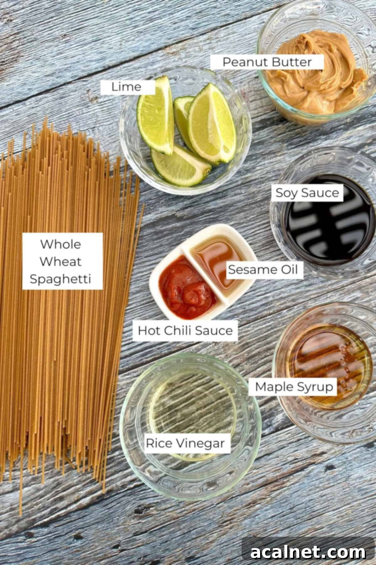 Ingredients for spicy peanut noodles in small bowls on a wooden table.