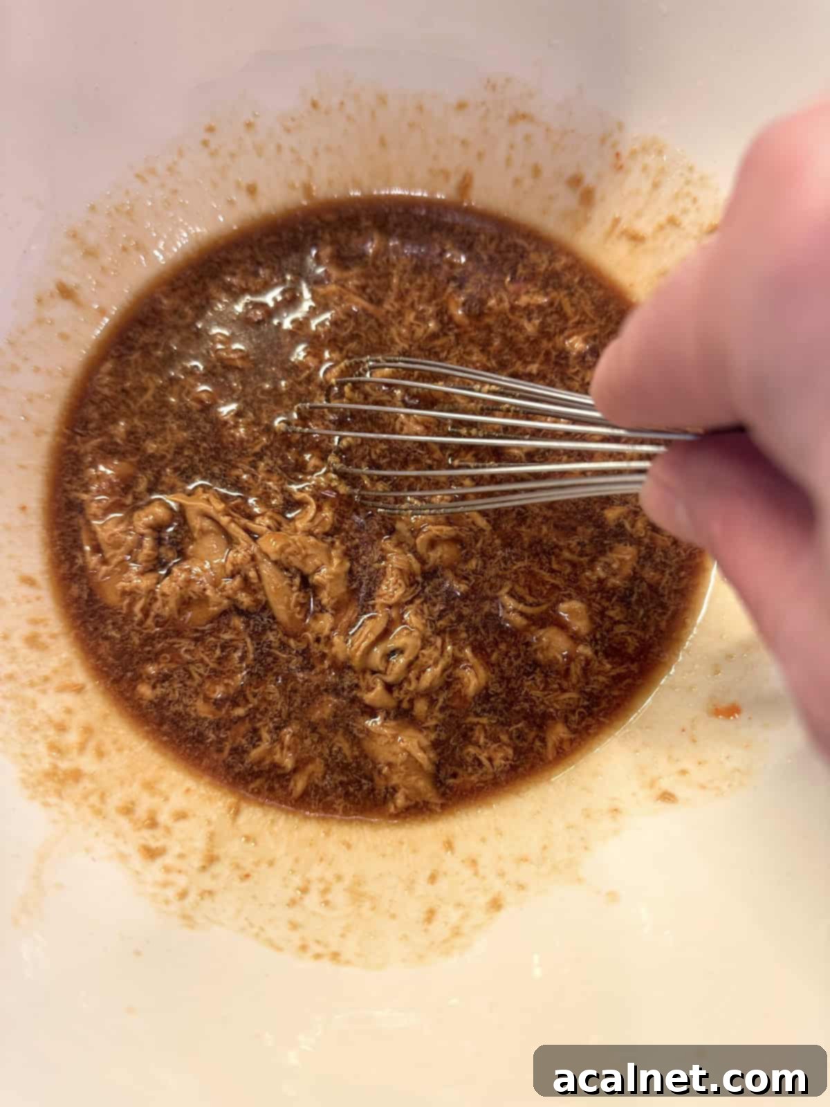 Peanut spicy noodle sauce in a bowl with a whisk.