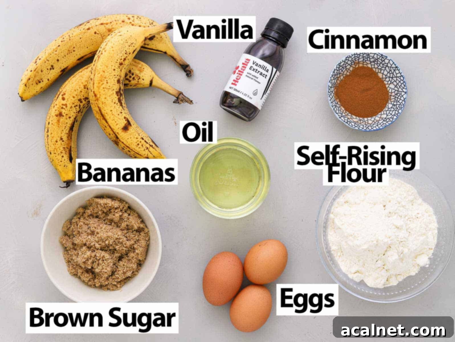 A selection of fresh ingredients including ripe bananas, eggs, oil, brown sugar, and flour, arranged on a grey surface for a Remoska banana bread cake.