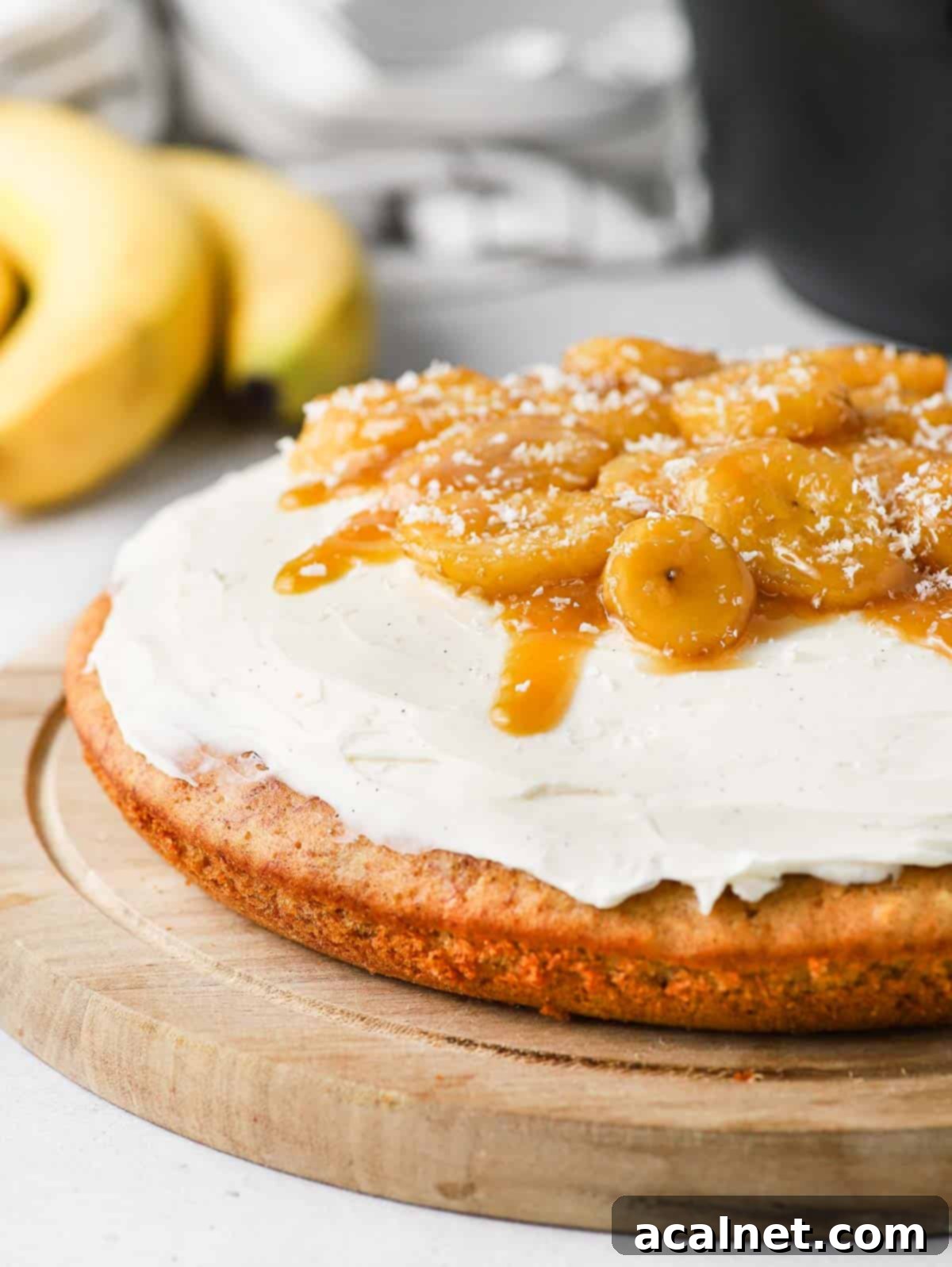 Close up on the creamy cream cheese frosting and glossy caramelized bananas topping a slice of banana bread cake.