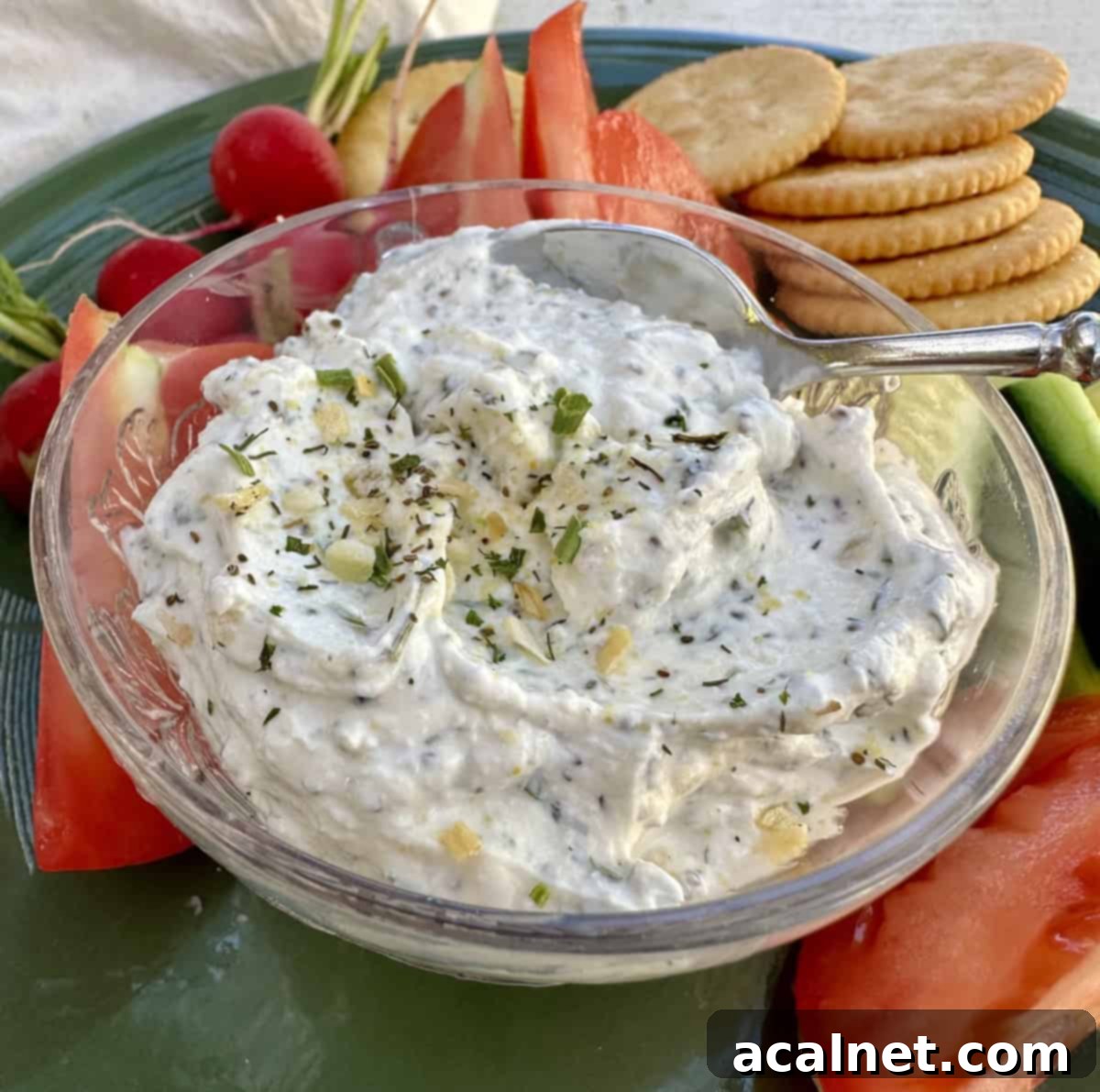 Creamy garlic and herb dip served in a rustic dish, surrounded by vibrant chopped vegetables and crisp crackers, ready for a gathering.