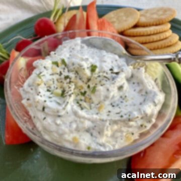 Creamy garlic and herb dip in a rustic dish, surrounded by vibrant chopped vegetables and crisp crackers, ready for a gathering.
