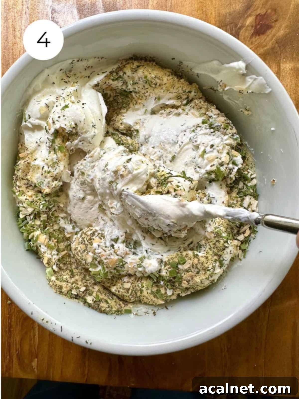 The blended dried herbs thoroughly mixed into the creamy sour cream, creating a luscious, speckled herb and garlic dip in a bowl.