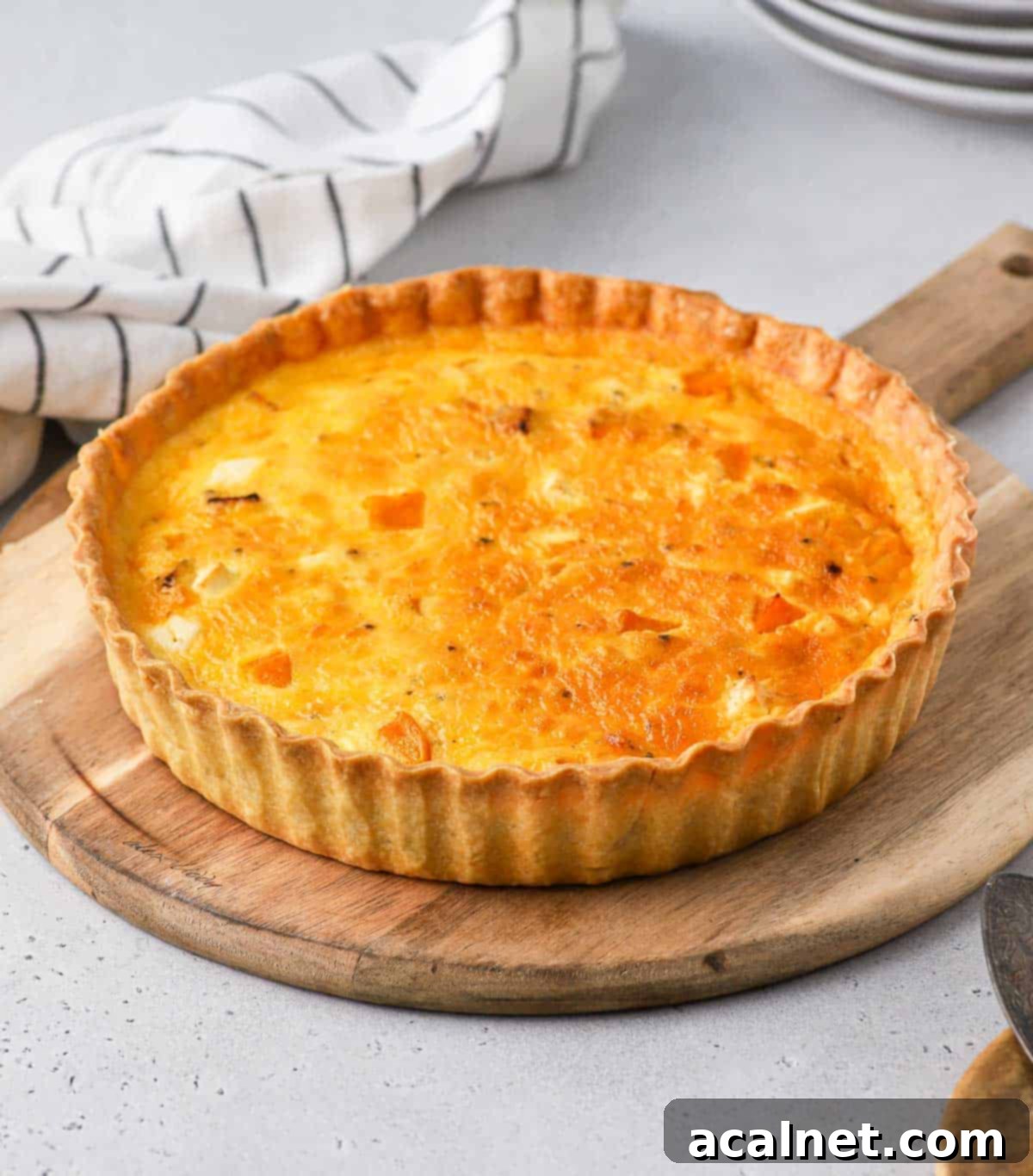 Quiche on a wooden round board.