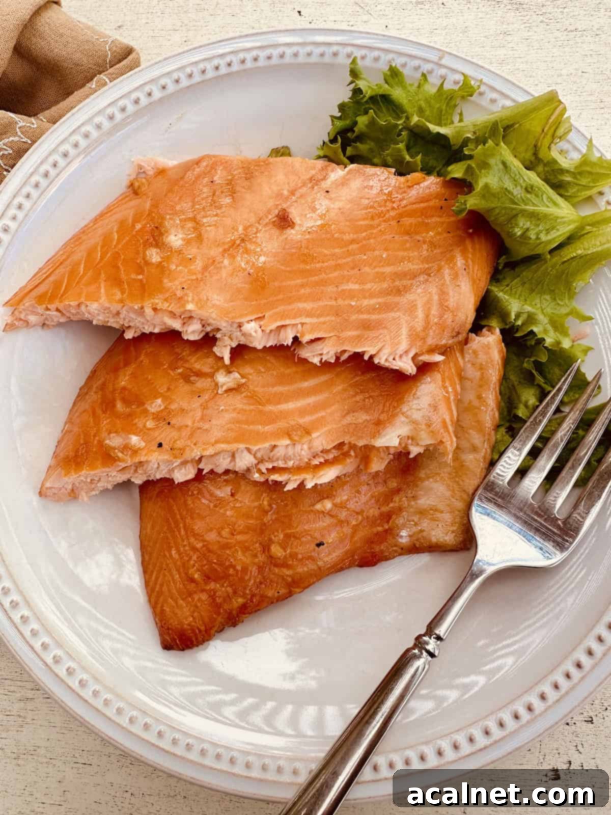 Three generous portions of smoked salmon served on a plate with fresh lettuce and a fork, ready to be enjoyed.