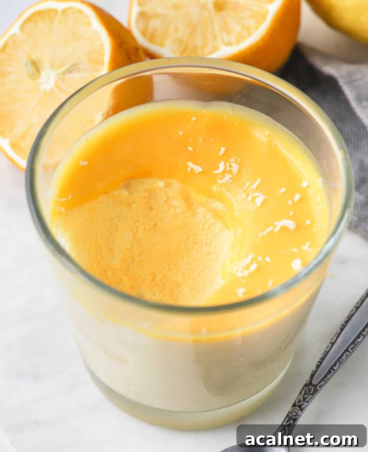 Zesty Lemon Mousse & Curd Delight 8 A spoon scooping out a generous portion of creamy lemon mousse from a glass cup, showing its light texture.