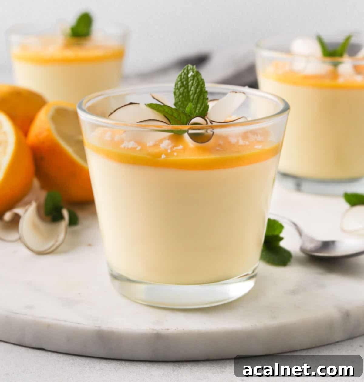 Zesty Lemon Mousse & Curd Delight 9 Three glass cups of lemon mousse topped with lemon curd, arranged artfully on a marble board, ready to be served.