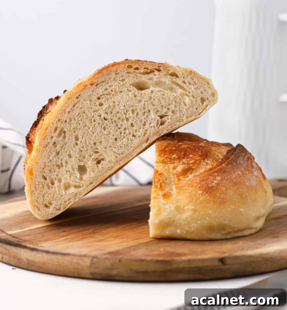 No Knead Bread in the Remoska 9 Two halves of freshly baked No-Knead bread on a wooden board, showing the open crumb structure.