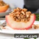 Remoska's Golden Crumble-Baked Apples 9 A perfectly baked apple with a golden, crunchy crumble topping, sliced in half to reveal its tender interior.