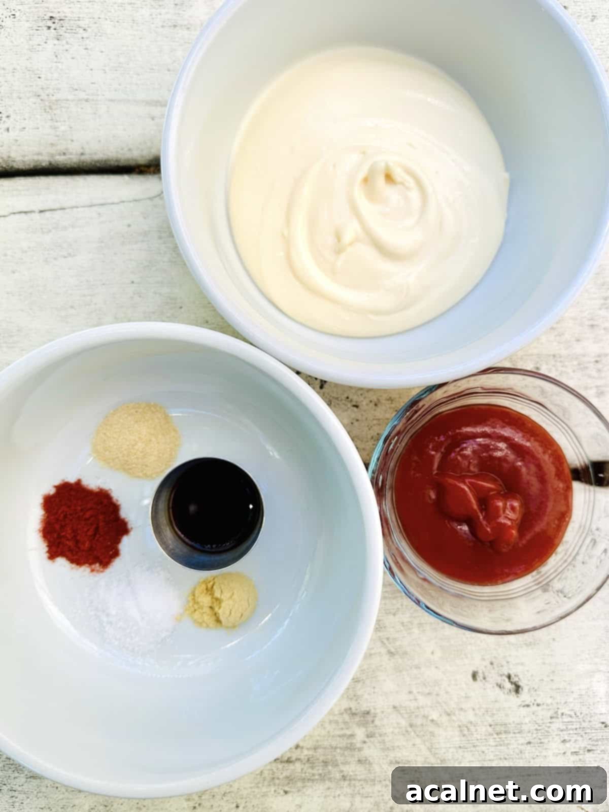 Ultimate Fry Dip 4 Small white bowls filled with the individual ingredients for French fry sauce, including creamy mayonnaise, rich red ketchup, and various spices like ground mustard and smoked paprika, neatly arranged on a light wooden table.