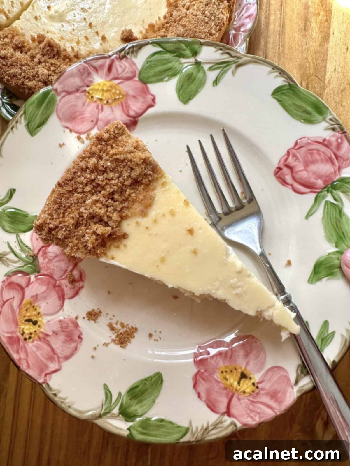 A single, elegant slice of vanilla cheesecake, impeccably plated with a fork, highlights its smooth texture and golden crust.