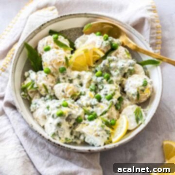 A vibrant bowl of Easy Potato Salad with Peas and Mint, garnished with lemon slices, a zesty twist on a classic.