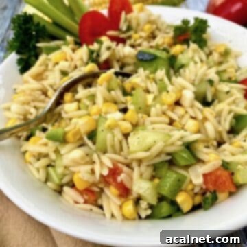 Fresh Sweet Corn Pasta Salad in a bowl, with a raw ear of corn in the background, highlighting its key ingredient.