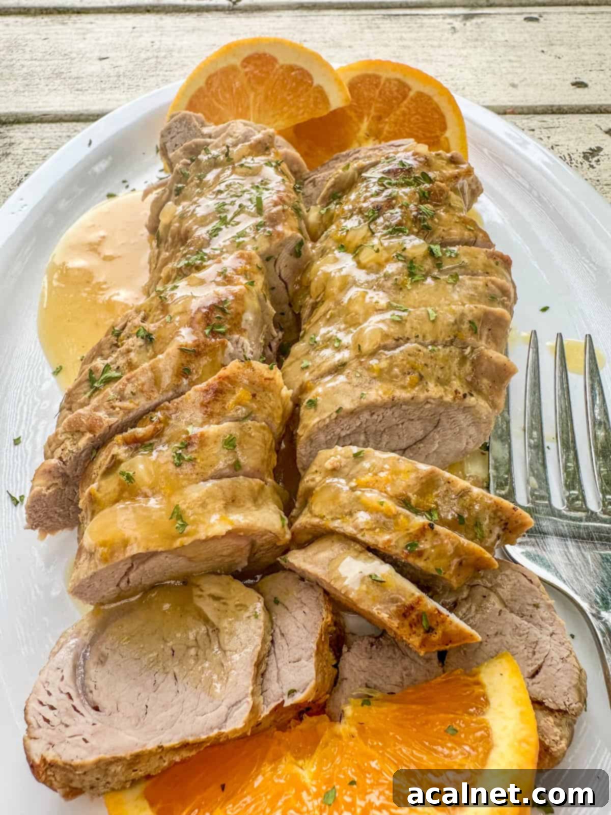 Boneless pork tenderloin slices with orange glaze and sliced oranges.