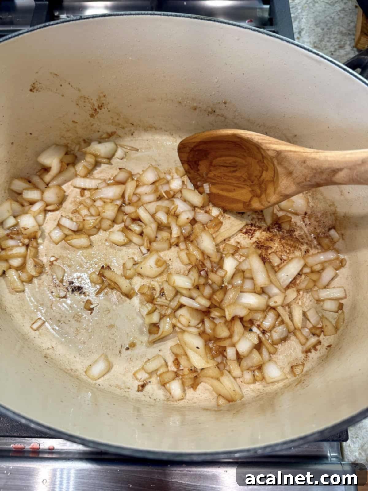 Diced onions in a pan with a wooden spoon.