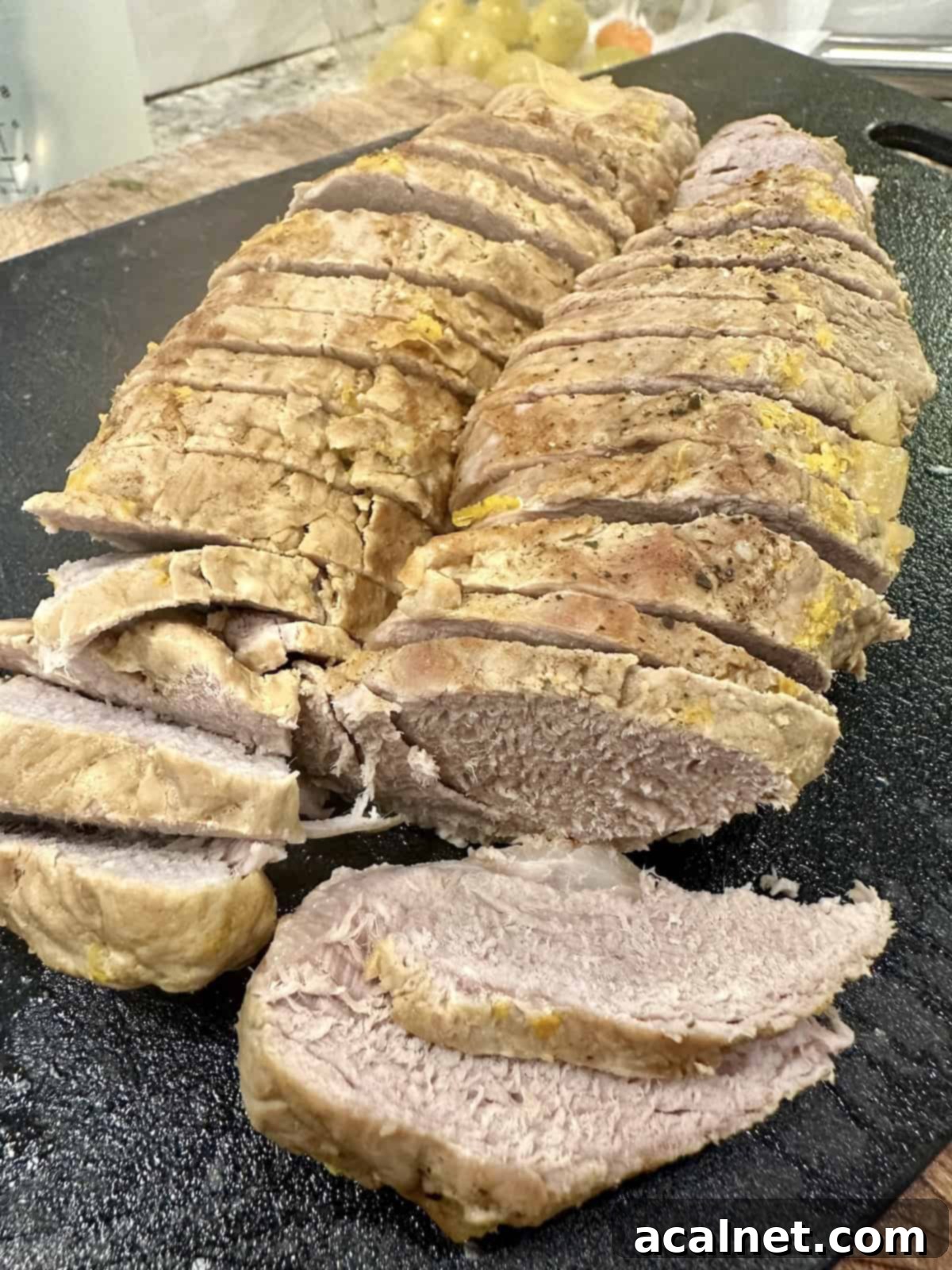 Sliced, cooked pork tenderloin on a cutting board.
