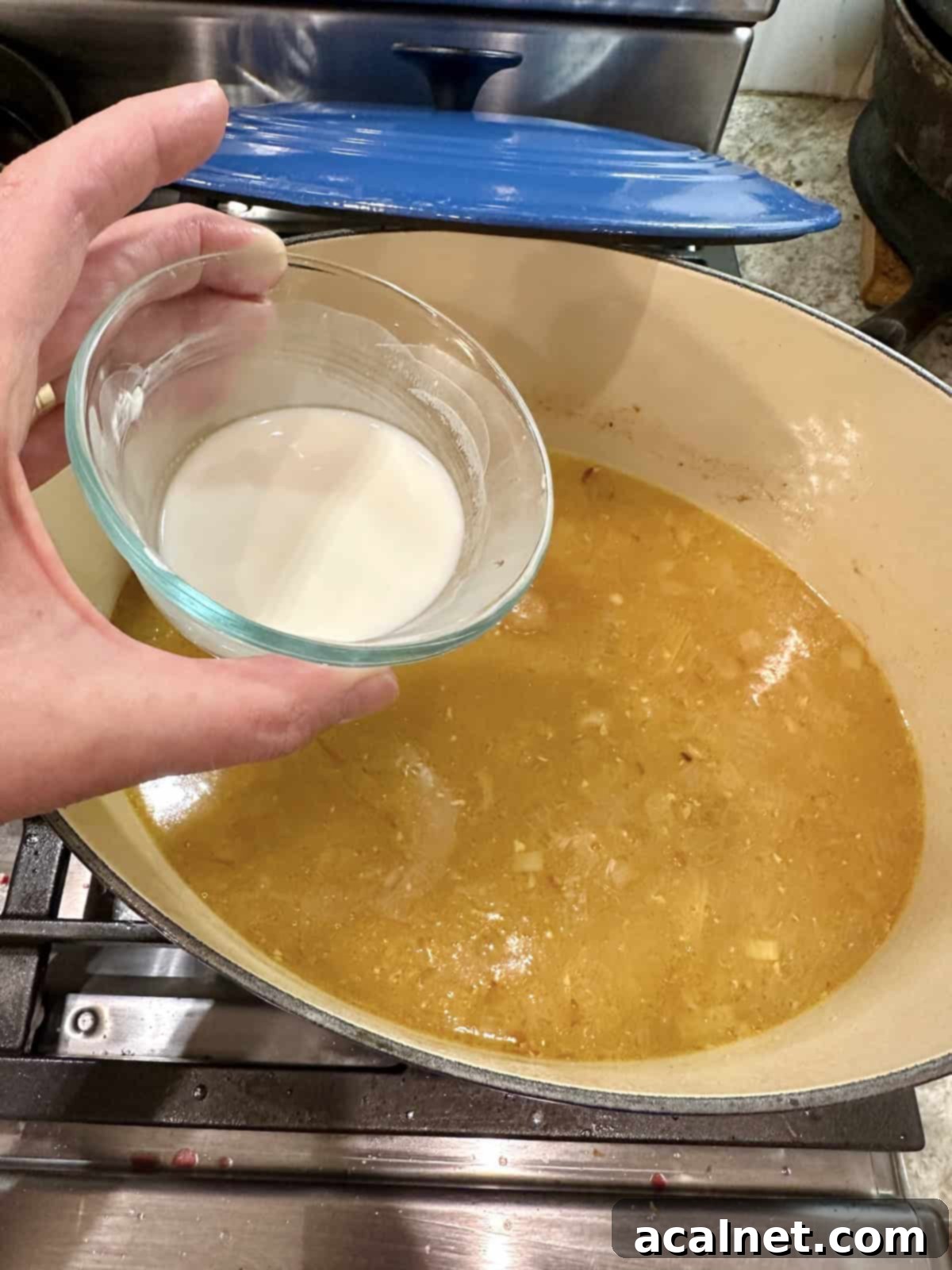 A bowl of cornstarch and a pan of orange sauce.