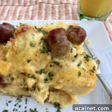 Cheesy Sausage and Egg Bake 11 A single serving of the hearty Cheese, Egg, and Sausage Casserole on a plate with a fork, accompanied by a glass of refreshing orange juice, ready to be enjoyed.