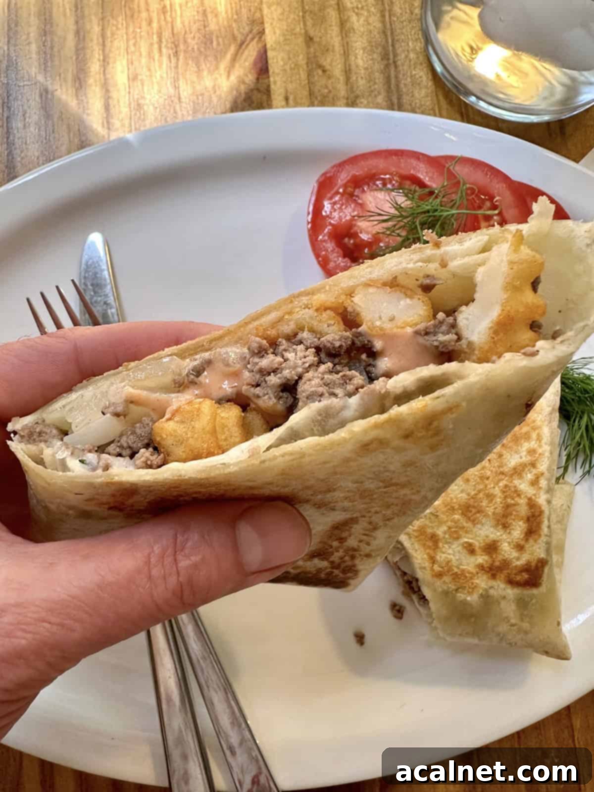 A half of a french taco, held over a plate.
