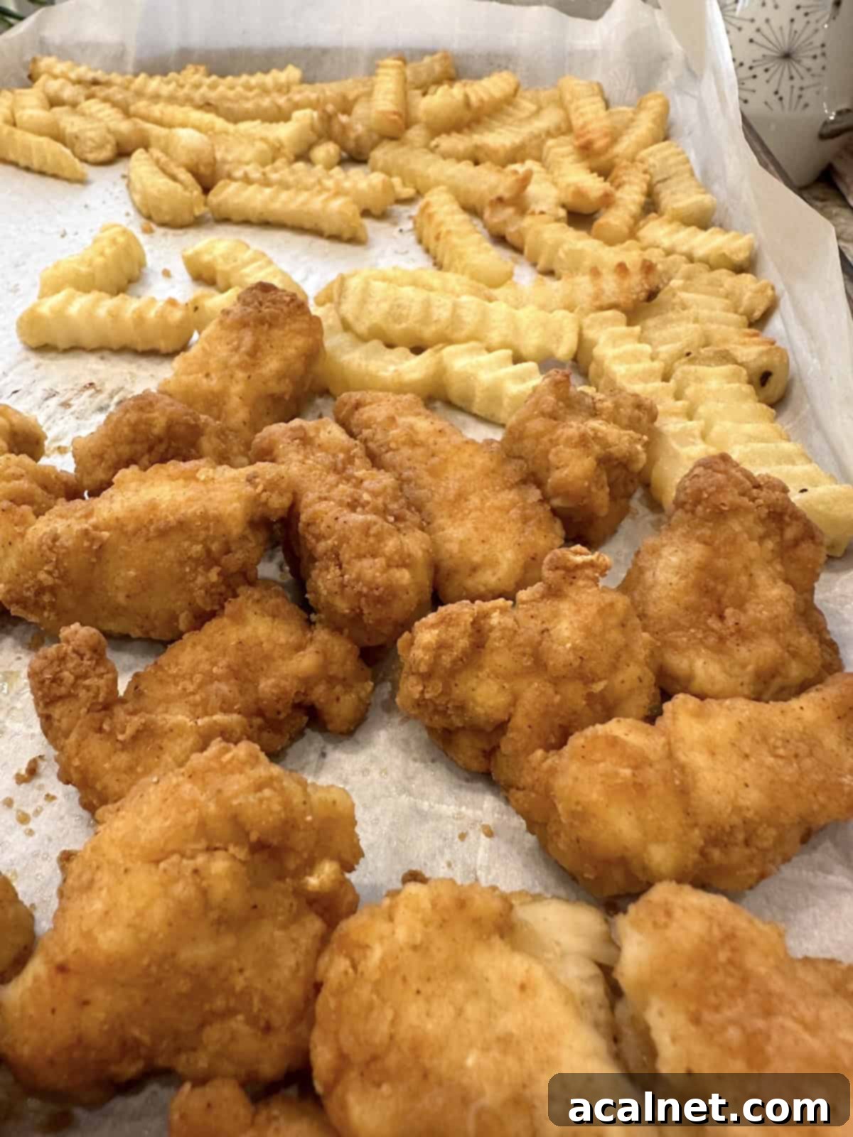 French fries and chicken nuggets on a baking sheet.
