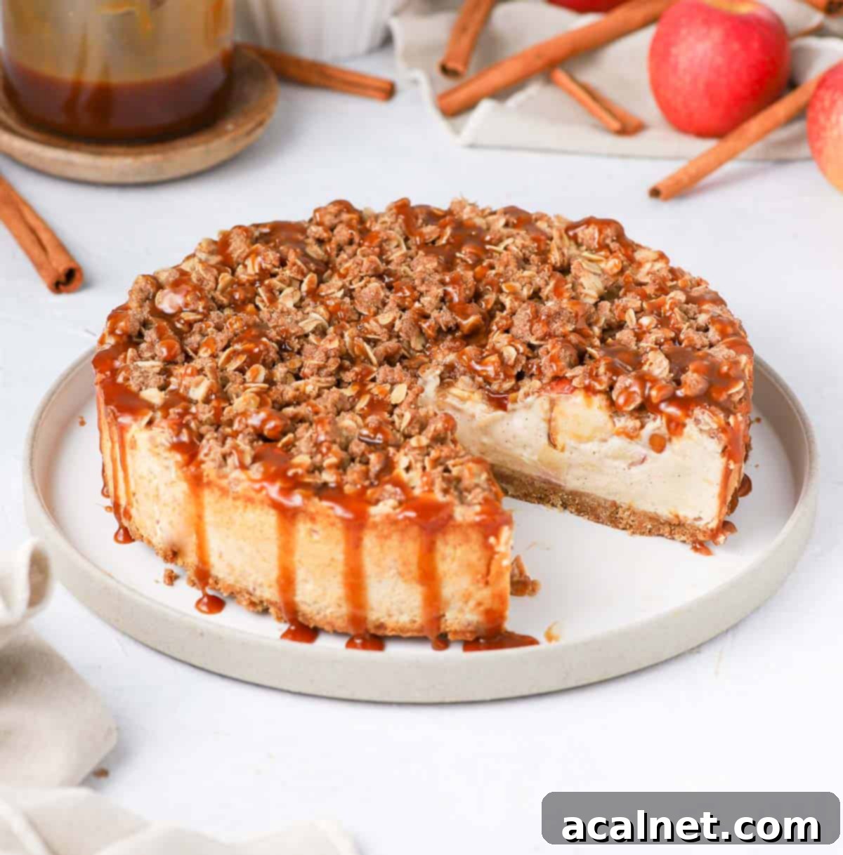 Spiced Apple Crumble Cheesecake 10 A whole apple crumble cheesecake on a cake stand with one slice already taken out, revealing the creamy interior.