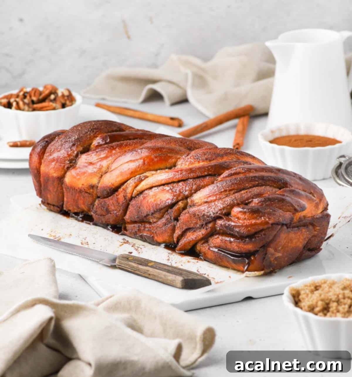 Side view of a freshly baked Cinnamon Babka on a white ceramic board, showing the distinct twisted layers of cinnamon.