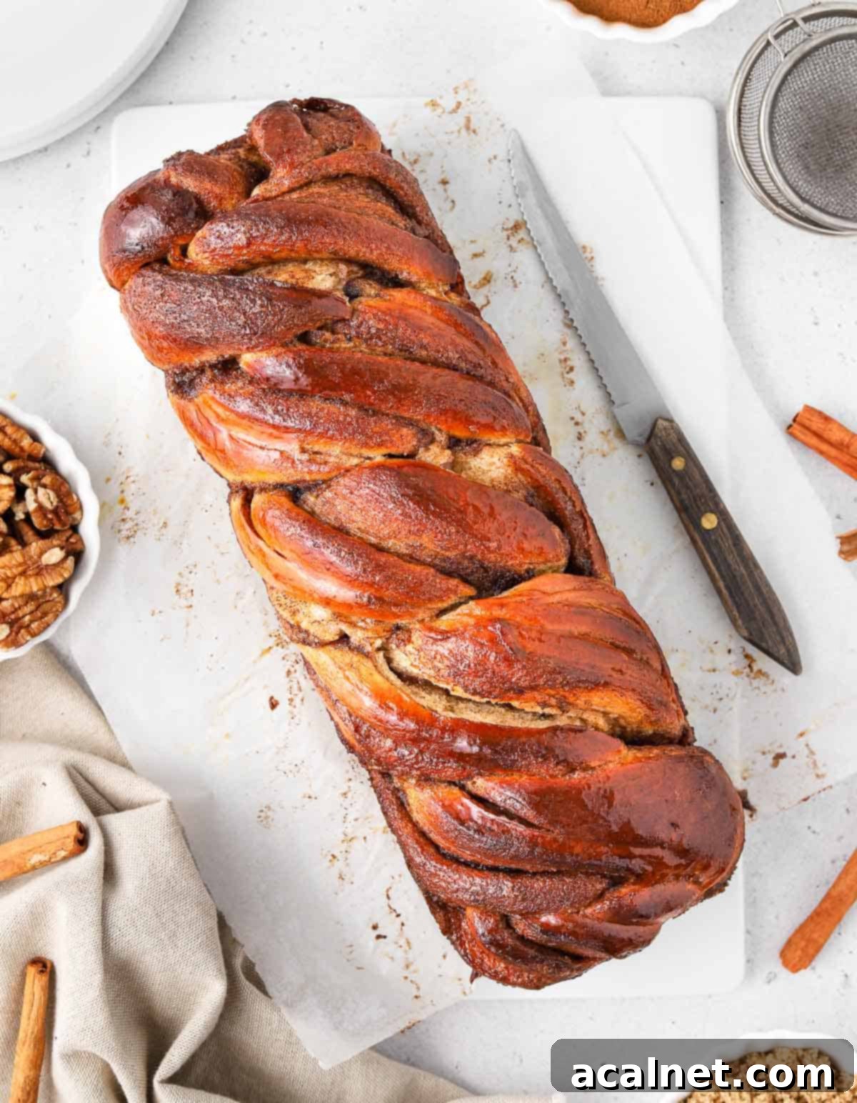 A whole Cinnamon Babka loaf seen from above on a white tray, showcasing its beautiful braided crust.