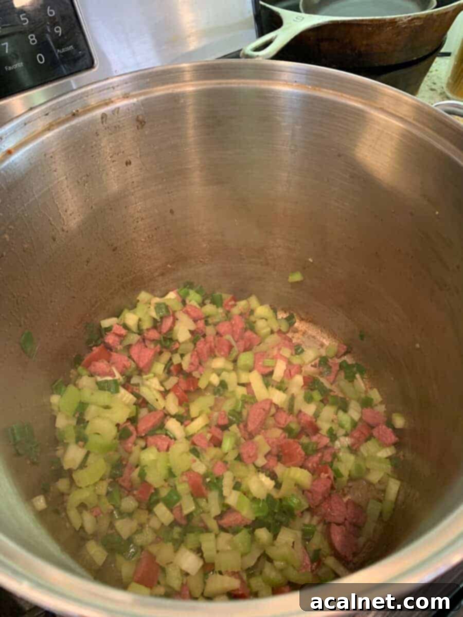 Diced celery, onion, and sausage browning in a large stock pot, creating a flavorful base.