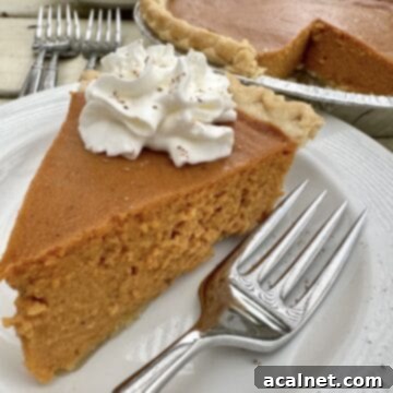 A perfectly sliced pumpkin pie on a plate, garnished with a fork, ready to be enjoyed.