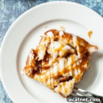 A delectable apple pie bar resting on a white plate, accompanied by a fork, showcasing its crisp crust and sweet apple filling.