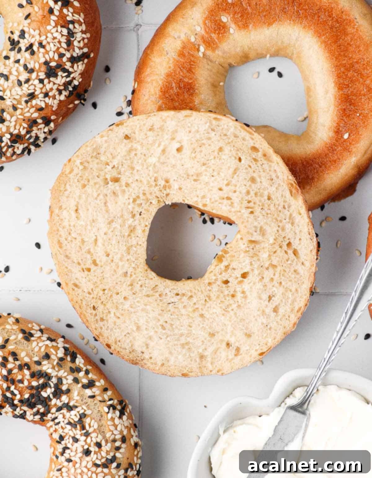 A homemade sesame bagel sliced in half, revealing its soft, airy crumb.