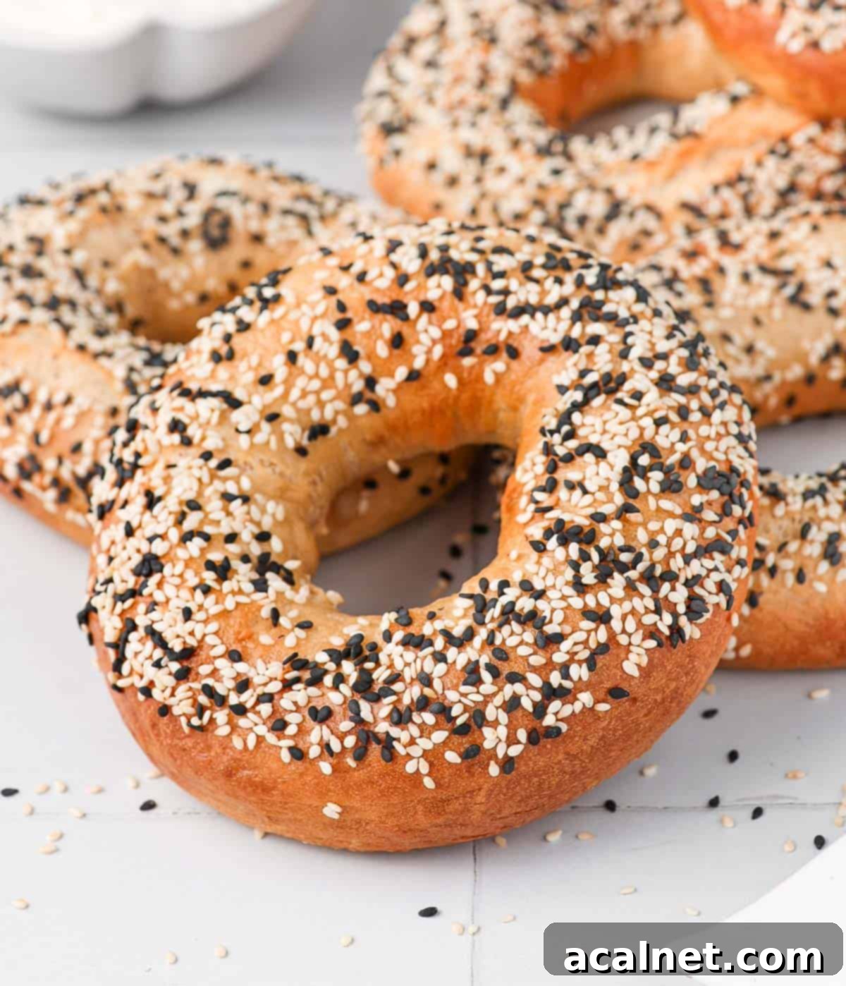 Close up on a stack of freshly baked sesame bagels, highlighting their crisp exterior and beautiful golden color.