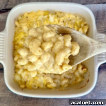 A large spoonful of smoked gouda mac and cheese held over a baking dish filled with the mac and cheese.