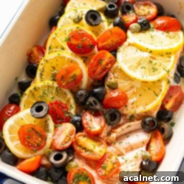 A vibrant baking dish featuring baked salmon topped with colorful cherry tomatoes, olives, and lemon slices.
