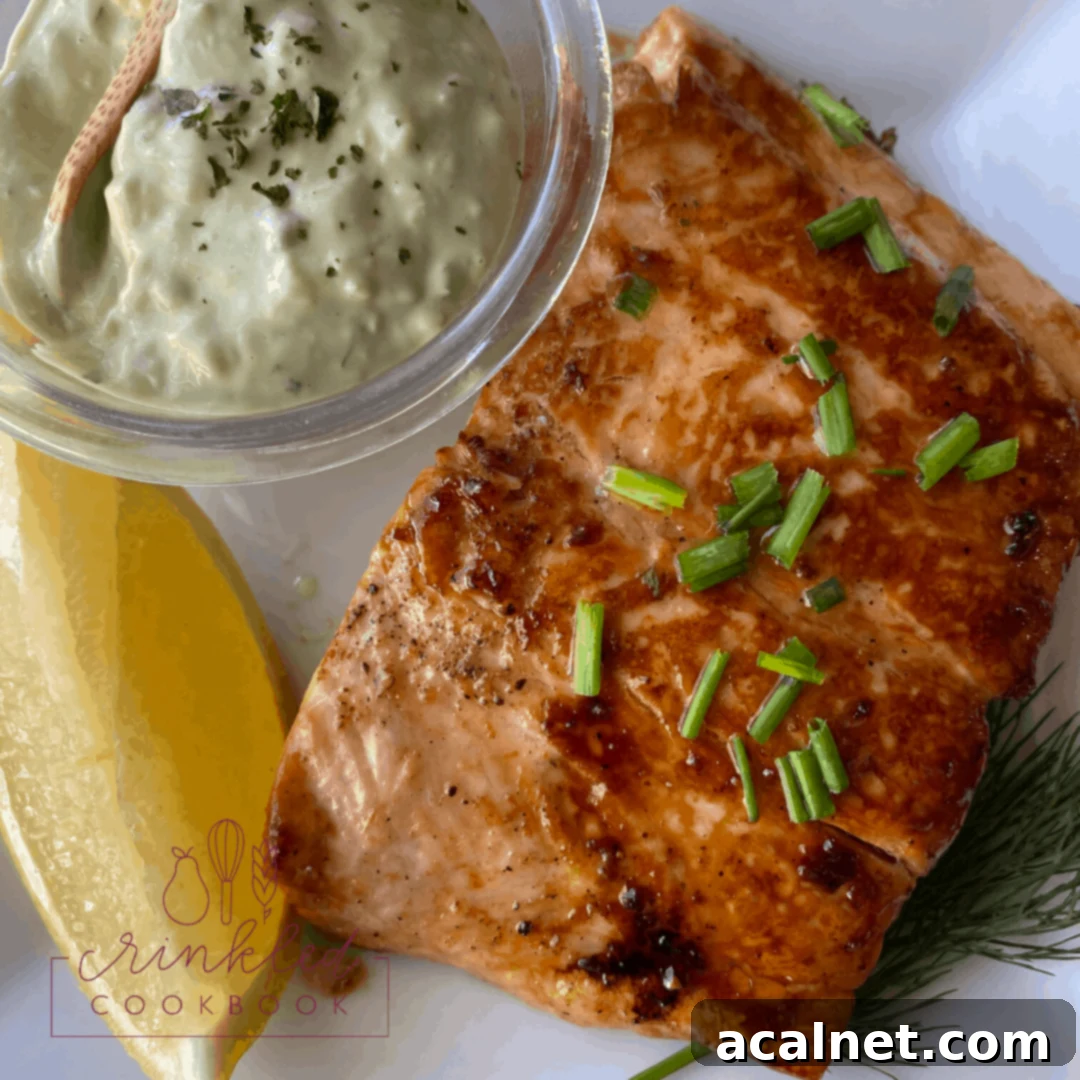 Skillet-glazed salmon on a plate, served with lemon wedges and a side of tartar sauce.