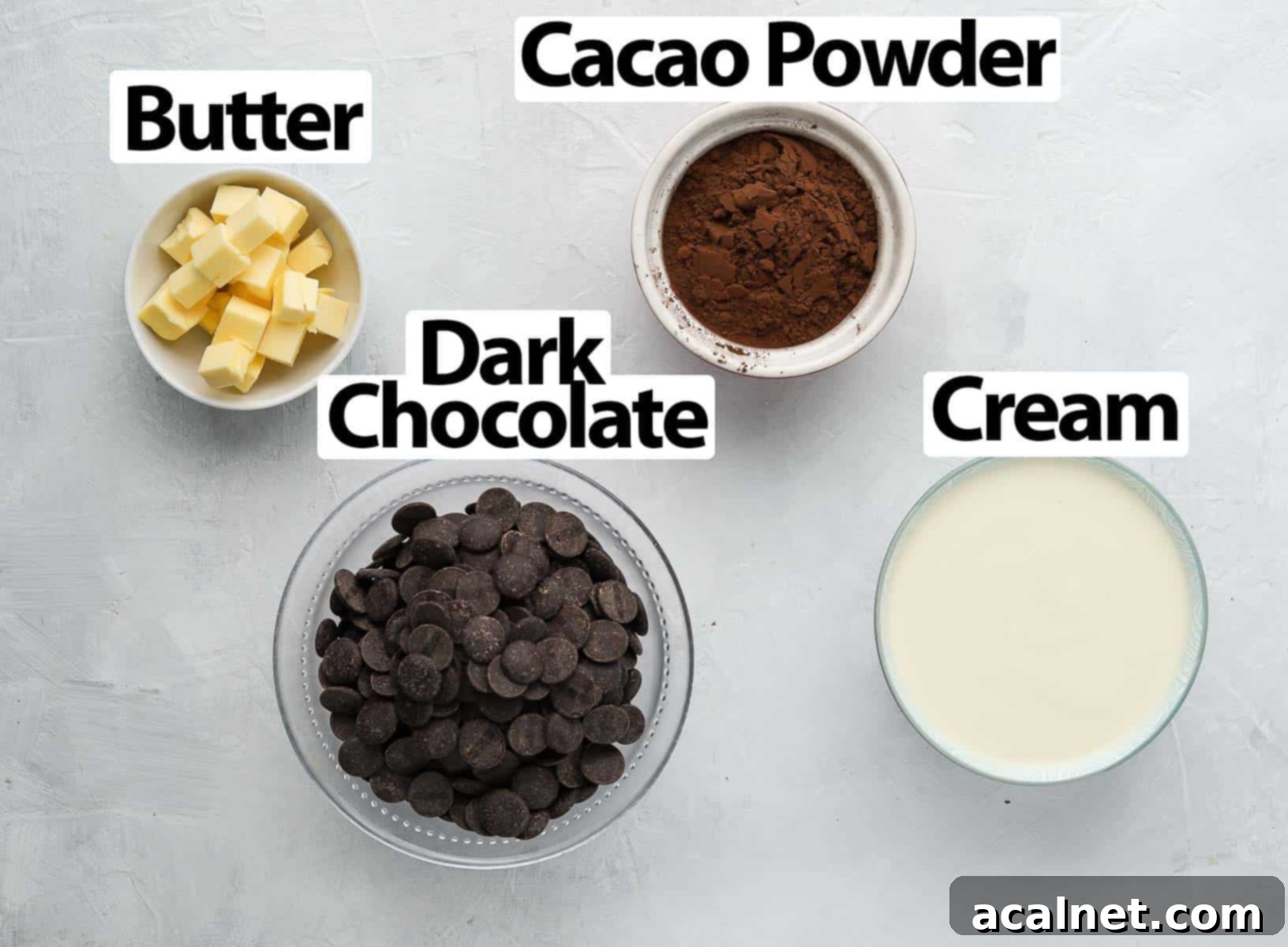 Ingredients for French Chocolate Truffles arranged on a white surface, including chocolate, cream, butter, and cocoa powder.