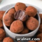 One bite taken off a chocolate truffle stacked inside a small grey bowl.