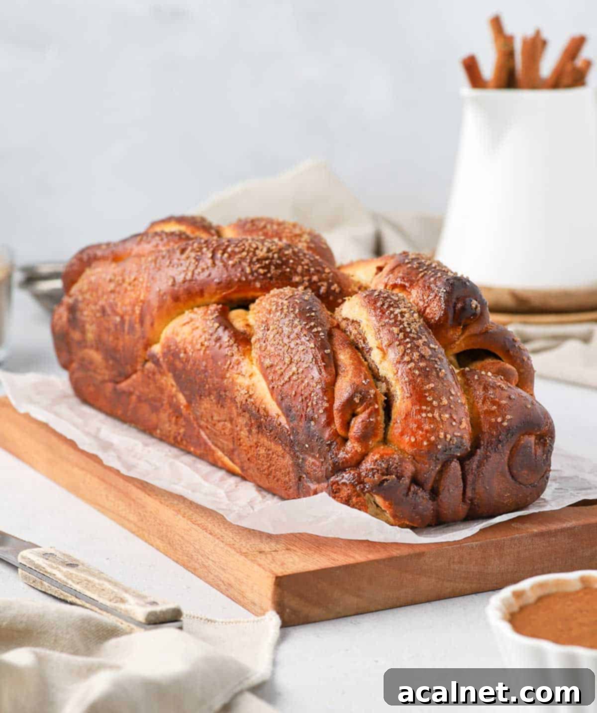 Freshly baked cinnamon roll bread loaf resting on a wooden board.