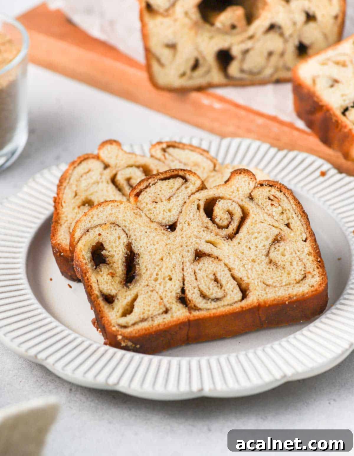 Two slices on cinnamon bread on a small white plate, showing the beautiful cinnamon swirls.