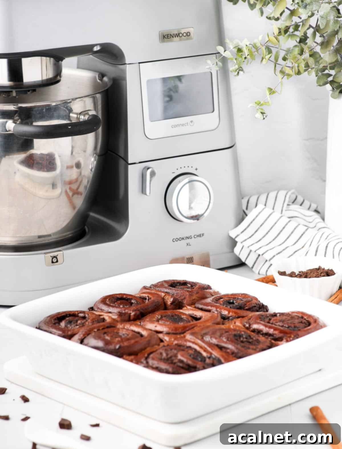 A pan of baked triple chocolate cinnamon rolls with a Kenwood Cooking Chef XL Stand Mixer visible in the background, showcasing the equipment used.